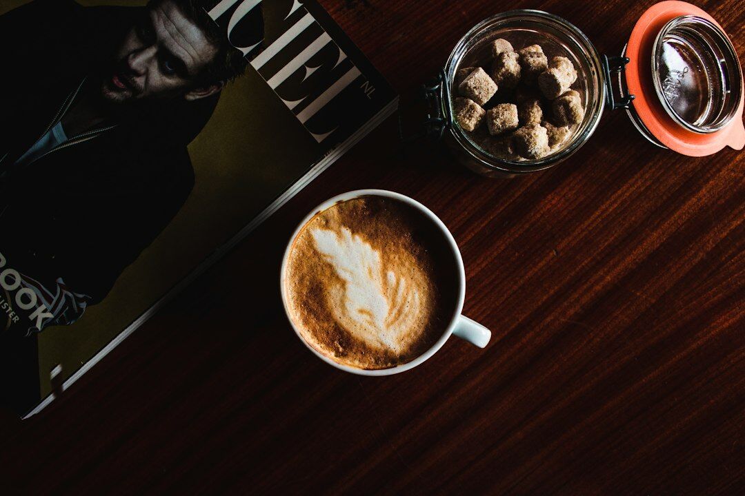 Overhead flat lay of camera, notebook, printed photographs and coffee on a wooden table